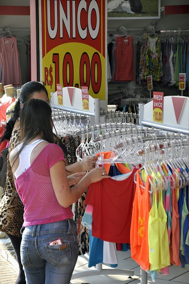 Pessoas buscam melhores preços em vestuário. duas mulheres olhando roupas no brechó